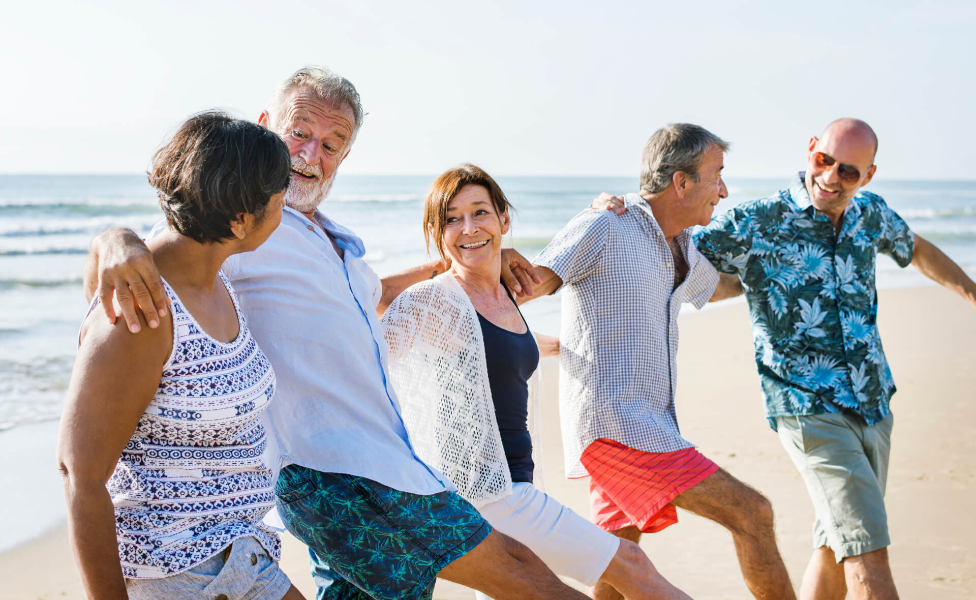 mixed group senior friends walking at the beach